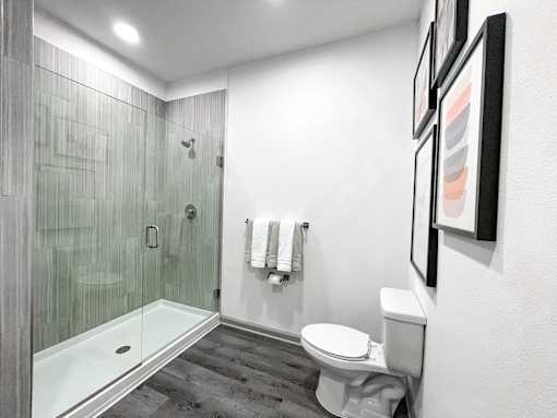 A white toilet sits next to a white wall in a bathroom.
